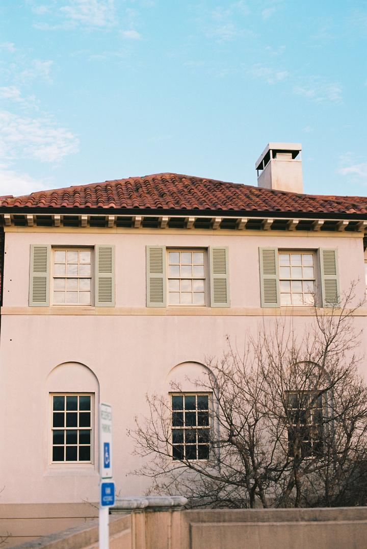 Stucco chimney above a red tile roof and shuttered windows