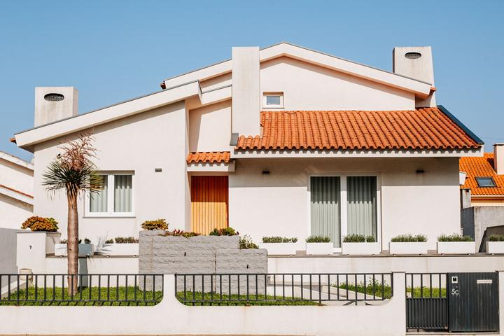 Cream stucco house with chimney stacks above a tile roof
